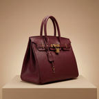 Maroon handbag with gold hardware on a beige background