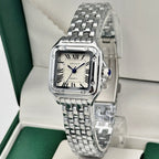 Silver wristwatch with a white face on a green and white background